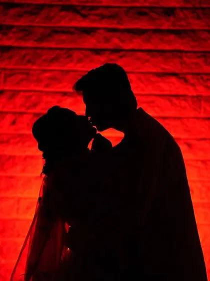 A powerful and artistic silhouette of a couple against a bold red background. This is a perfect example of our cinematic style, using dramatic lighting to create a memorable and emotional image.