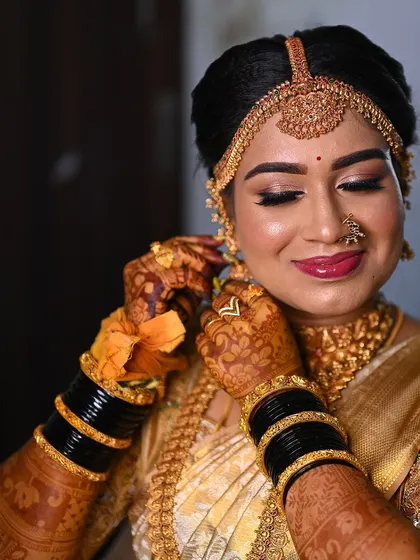 The bride adjusting her earring, providing a perfect view of the intricate mehendi stain on her hands and fingers.