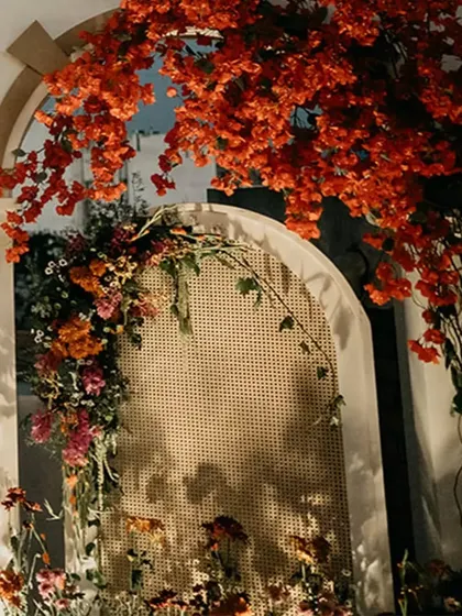 A close-up of the floral decor on the mandap arches. We used a mix of bright red bougainvillea and other colorful blooms, with a rattan screen adding a touch of texture.
