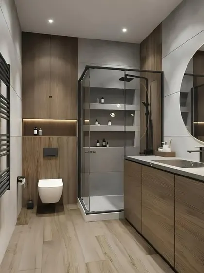 This design shows how to integrate storage seamlessly into a bathroom. The shower has built-in niches, and the wall behind the toilet includes a tall cabinet, all finished in a warm wood tone.