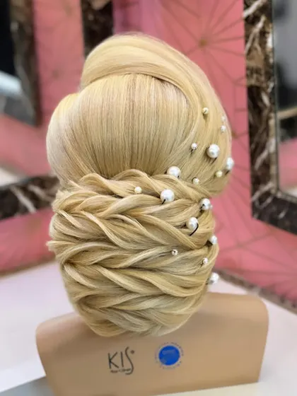 A close-up of the finished low bun, showcasing the detailed weaving and placement of pearls.