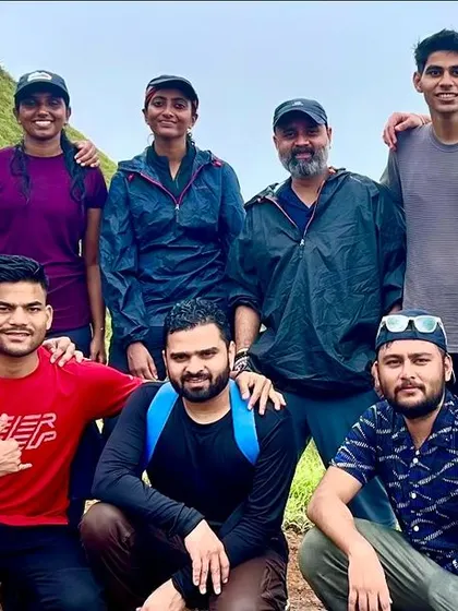 A group of friends huddle together for a photo on a green, misty trail.
