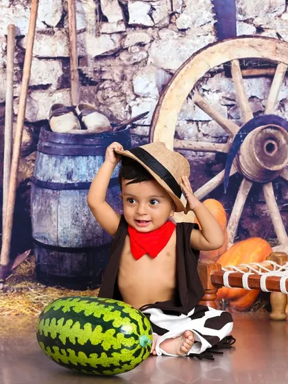 This little cowboy is tipping his hat. The rustic barn backdrop and props create an authentic and charming wild west scene.