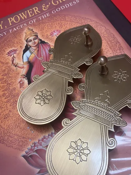 Beautifully crafted brass 'padukas' (sandals symbolizing the guru's feet) that I designed. They rest on a book about the goddess, blending devotion and wisdom.
