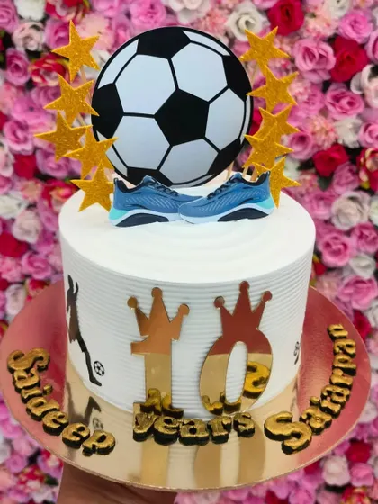 A football-themed cake for a 10th birthday. It features a 3D football, edible soccer shoes, and golden stars.