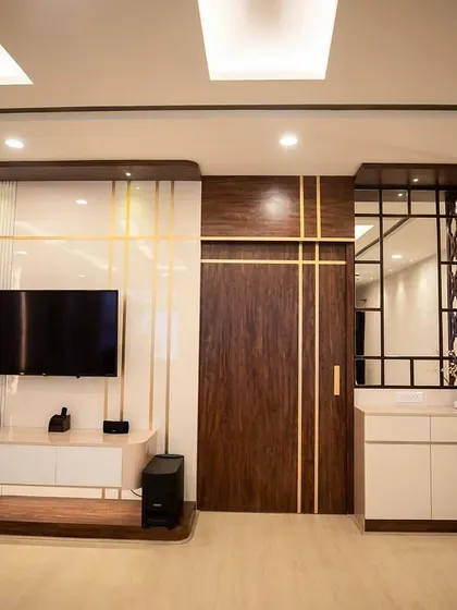 A perfect example of integrated design, where the living room, dining area, and pooja space flow into one another. The use of wood, white panels, and gold accents creates a cohesive and sophisticated look.