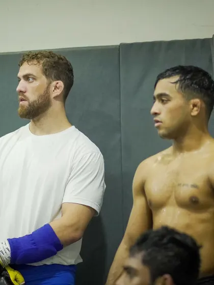 Two fighters, focused and ready, between sparring rounds. The intensity and mutual respect in the room are palpable.