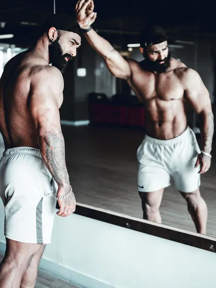 The mirror is the best training partner for posing. Here, I am analyzing my front relaxed pose, making micro-adjustments to improve the presentation.