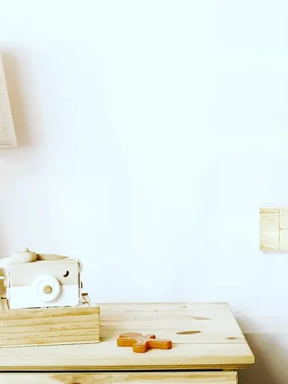 A wooden touch panel installed on a clean, white wall next to a nightstand. This shows how our natural material panels can bring warmth and texture to a minimalist space.