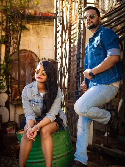 A stylish pre-wedding shot with the couple in matching denim, posing in a rustic, industrial setting. This showcases a more edgy and fashionable approach to engagement photos.