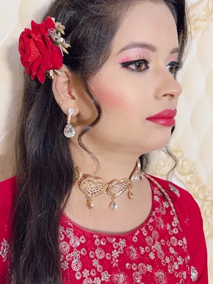 A beautiful party look with a red outfit and a fresh rose in her hair.