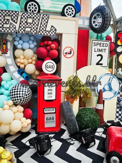 A close-up of the main backdrop shows the detailed props, including a vintage gas pump, a "Speed Limit 2" sign, and a character cutout, all surrounded by a cascade of balloons.