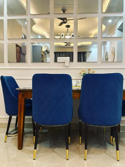 A close-up of the quilted velvet dining chairs, showing the detail of the fabric and the gold-tipped legs that add a touch of glamour.