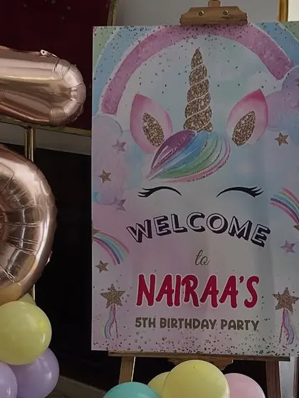 A welcome sign for a unicorn party, paired with a large foil number '5' balloon to highlight the milestone.