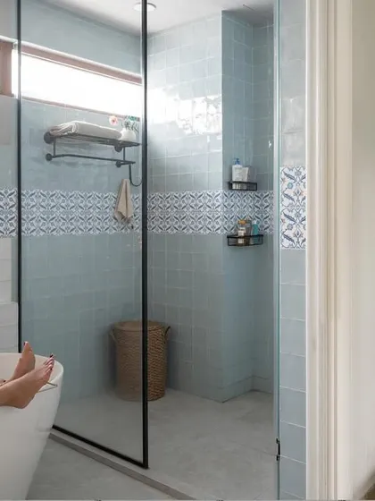 A relaxing soak in the tub in the Dhaka home. This bathroom combines modern fixtures with patterned tiles and an exposed brick accent wall, creating a space that feels both contemporary and full of character.