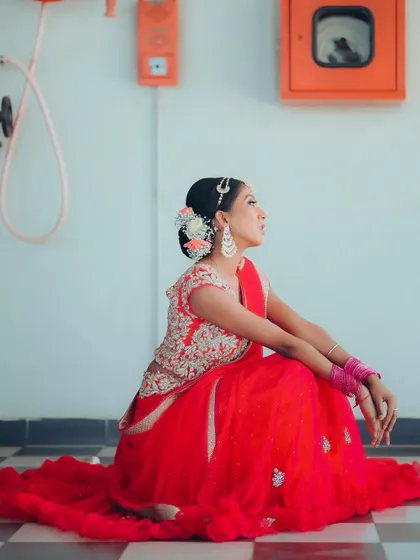 A side profile of the seated bride. This angle highlights her elegant posture and the intricate details of her hair and blouse.