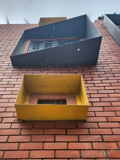 A detail shot of the quirky, angular window frames set against the brick wall. These small interventions add a pop of color and a modern, sculptural element to the school's facade.