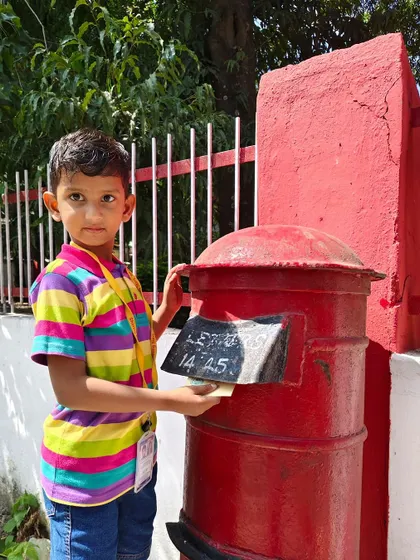 A student carefully posts his letter, learning about the postal system firsthand.