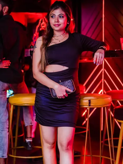 A guest in a stylish black dress, posing by the bar.