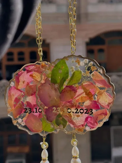 A pair of beautiful car hangings made with preserved pink petals and the couple's special date. It's a lovely way to carry a reminder of your love with you on all your journeys.