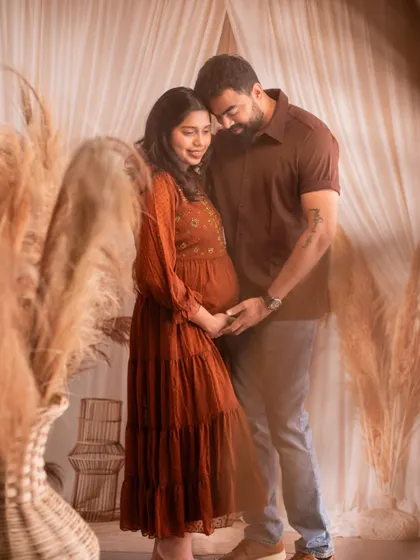 An intimate embrace, with both parents holding the baby bump. The soft lighting and neutral tones create a warm and loving image.