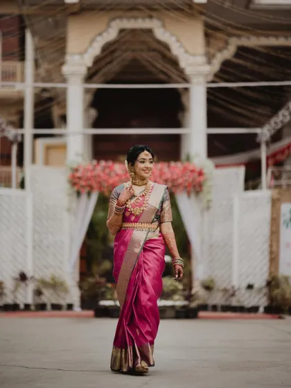 A full-length shot of Anushya in her stunning pink Kanjivaram saree. She looks the epitome of a graceful South Indian bride.