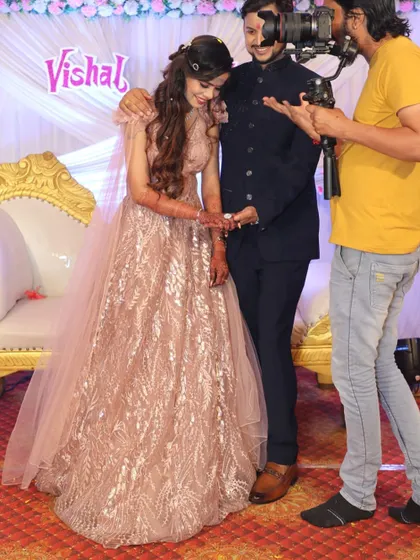 A behind-the-scenes look at an engagement ceremony. The bride looks beautiful in this sparkling pink gown, sharing a special moment with her partner.