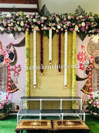 A beautiful pooja setup inspired by Pichwai art. We used traditional paintings of Lord Shrinathji as the centerpiece, framed by banana plants, fresh flowers, and elegant brass pots for a serene and artistic look.