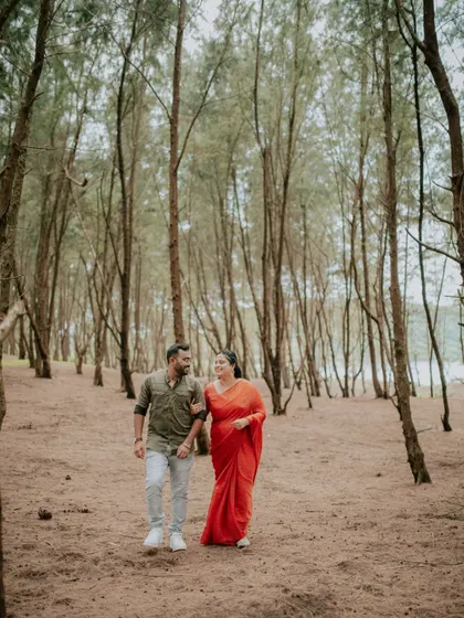 A wide shot of a couple walking through a beautiful forest, highlighting the scale and beauty of the location.