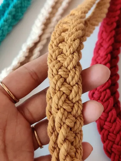 A close-up of the mustard lanyard being held, showing its flexibility and craftsmanship.