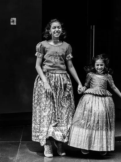 The infectious joy of siblings holding hands at a family event. This candid black and white photo captures the energy and connection between children during a celebration.