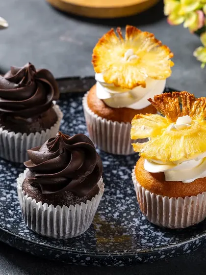 A close-up of chocolate and pineapple cupcakes for Ferns N Petals Luxe, showcasing two different flavors in one shot.