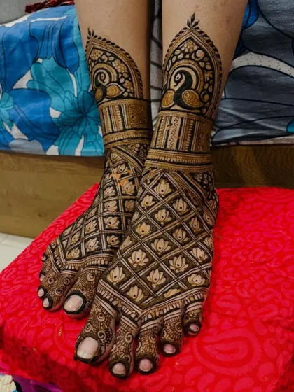 My bridal services include intricate designs for the feet. This particular design features a beautiful jaal pattern with lotus details, topped with elegant peacock figures at the ankle.