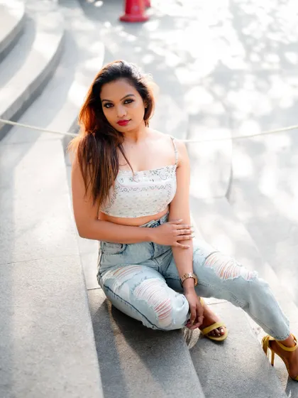 A relaxed portrait of a model sitting on stone steps. The natural light and casual pose create a beautiful and effortless fashion image.