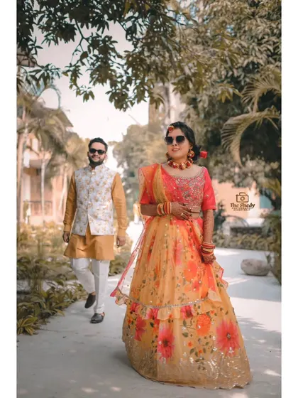 A candid shot of the couple walking together during their Haldi event. They look so happy and relaxed in their colourful outfits.