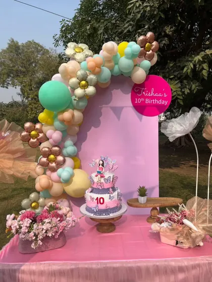 A close-up of the birthday cake and decor, showcasing the personalized details like the flower-shaped balloons and custom signage.