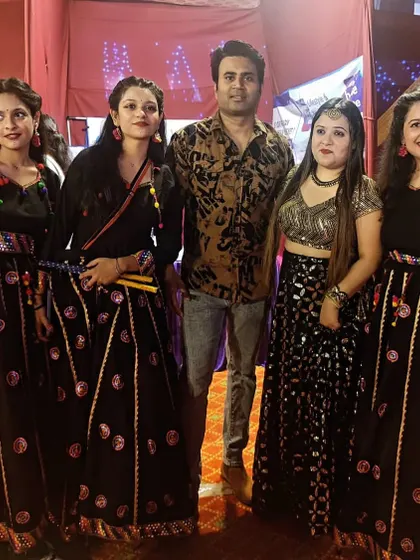 Instructor Robin with our talented dancers in their black and mirror-work costumes after a successful Garba performance.