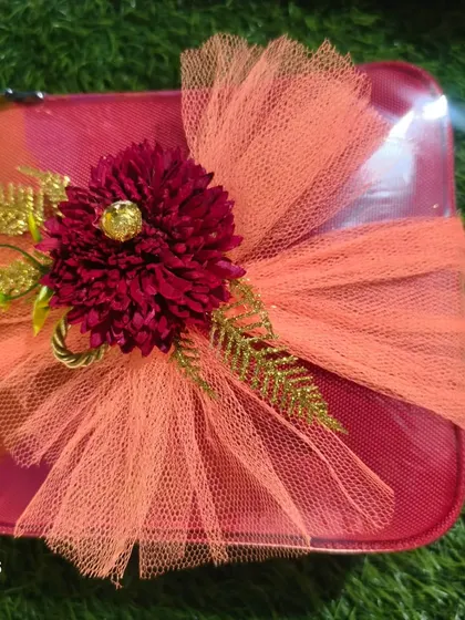 A small vanity case wrapped beautifully with orange net and a flower, a simple yet elegant gift for a Roka.