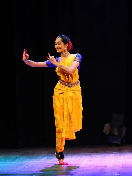 A graceful pose on one leg, demonstrating balance and control. The smile reflects the joy I find in performing these intricate choreographies.
