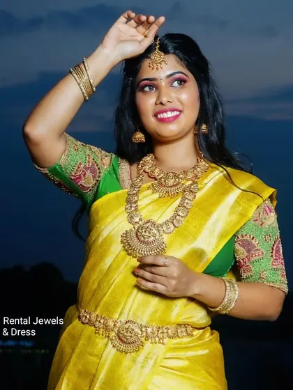 A beautiful bride glowing in our full temple jewellery set against the evening sky. This rental set includes the choker, haram, oddiyanam, and bangles.