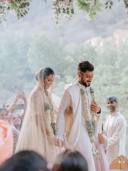 The couple walks hand-in-hand after their ceremony, surrounded by smiling guests. This shot captures the happiness and communal joy of the moment.