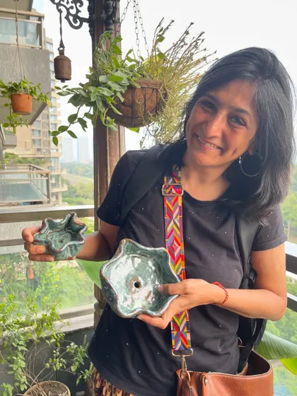 A student proudly holding her two unique, flower-like bowls, fresh from the kiln with a beautiful green glaze.