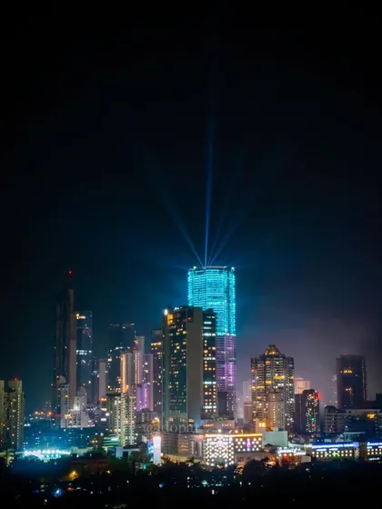 The Palais Royale skyscraper in Mumbai is lit up with blue lights and powerful spotlights, creating a beacon in the night sky.