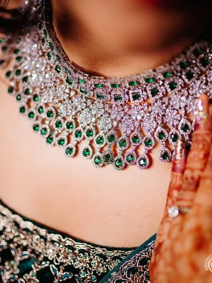 A close-up of a client's hand on her beautiful CZ and emerald choker. The details of the jewellery and the henna-adorned hand are just stunning.