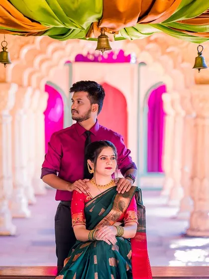 A regal portrait of a couple on a decorated swing. The rich colors of their outfits and the grand setting create a very elegant and traditional feel.