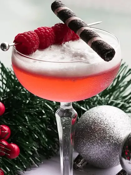 Another one of our festive creations, a raspberry foam cocktail garnished with a chocolate wafer, set against a Christmas backdrop.