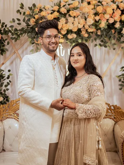 A classic portrait of the newly engaged couple, Nayan and Disha, posing together against a beautiful floral backdrop.
