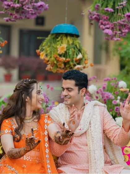Pure joy and laughter. This candid shot captures the couple sharing a fun moment during their Mehendi celebration.
