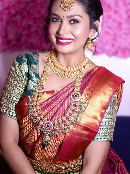 A happy bride on her wedding day, wearing a full kemp and green stone bridal set. The jewellery perfectly matches her beautiful silk saree.
