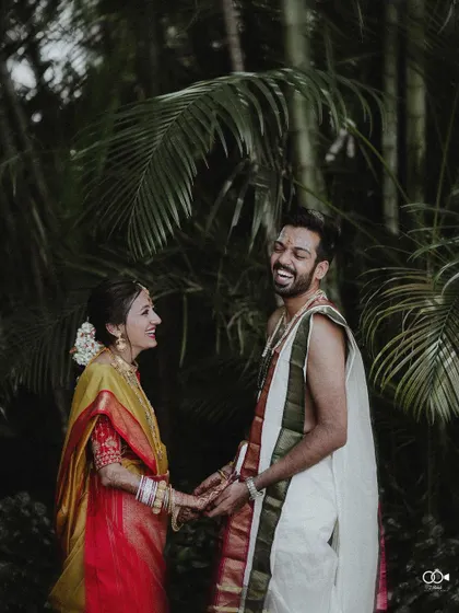A happy, candid portrait of the couple sharing a laugh in a lush, green setting after their ceremony.
